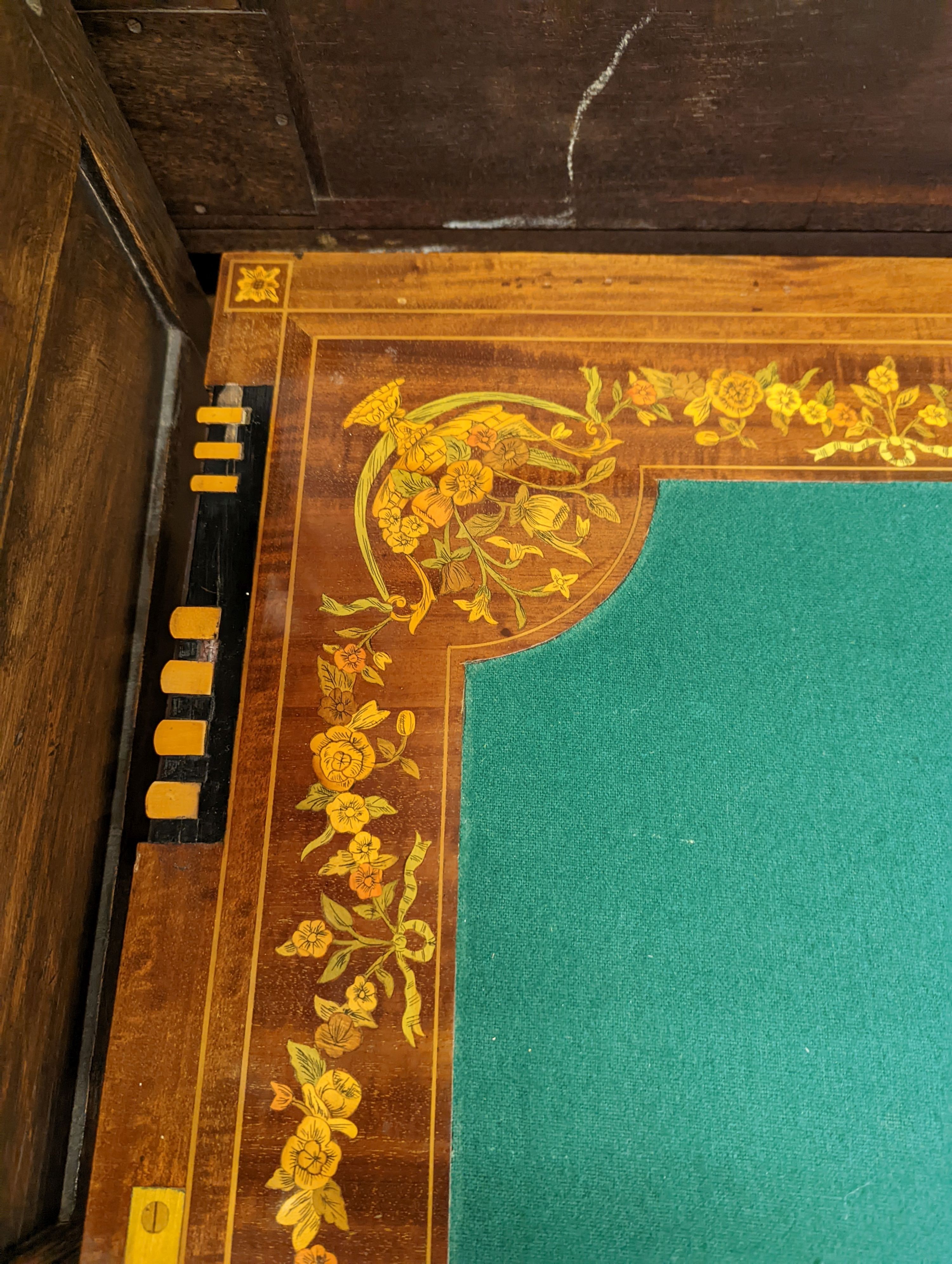 An Edwardian marquetry inlaid mahogany folding games table by W. Thornhill & Co., London, the interior baize lined surface with cribbage board and hinged markers, width 76cm, height 76cm